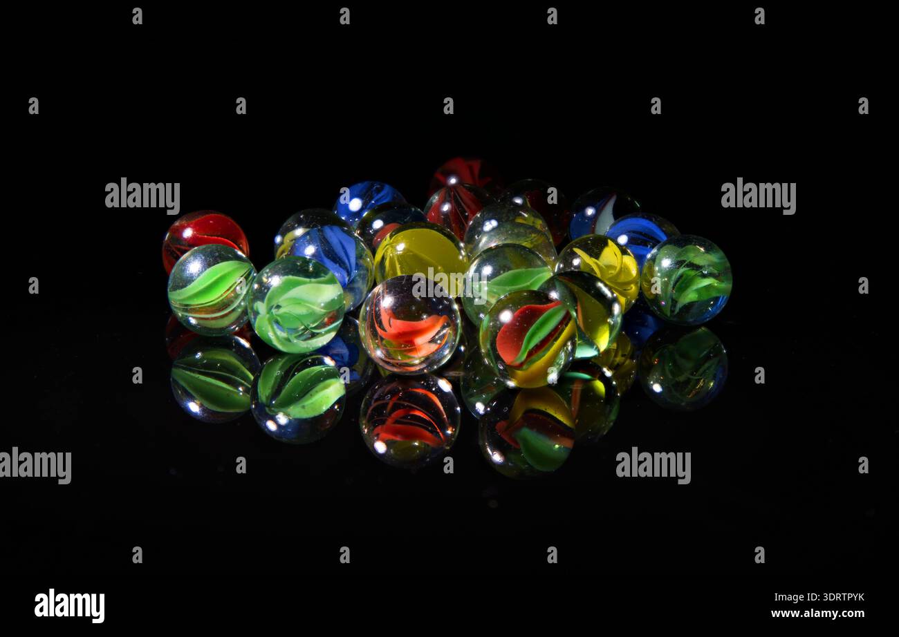 biglie giocattolo in vetro colorate con riflessi su sfondo nero Foto Stock