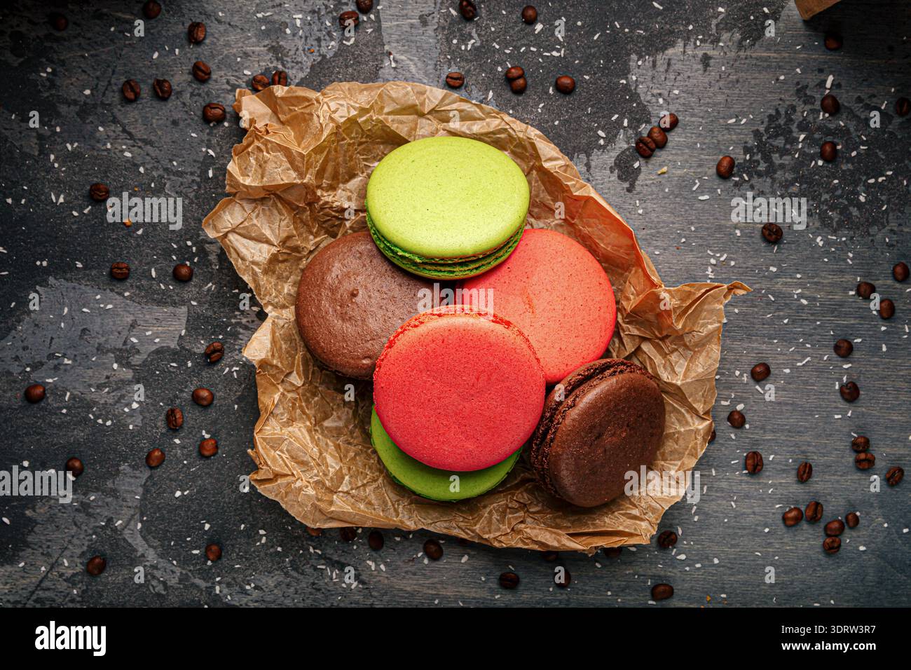 Macaron colorati su carta con chicchi di caffè Foto Stock