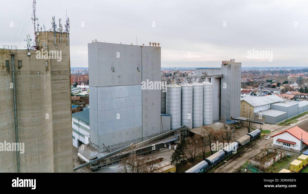Veduta aerea del complesso industriale, il suo calcestruzzo duro che contrasta con i colori tenui dell'area urbana circostante, Sremska Mitrovica, Vojvod Foto Stock