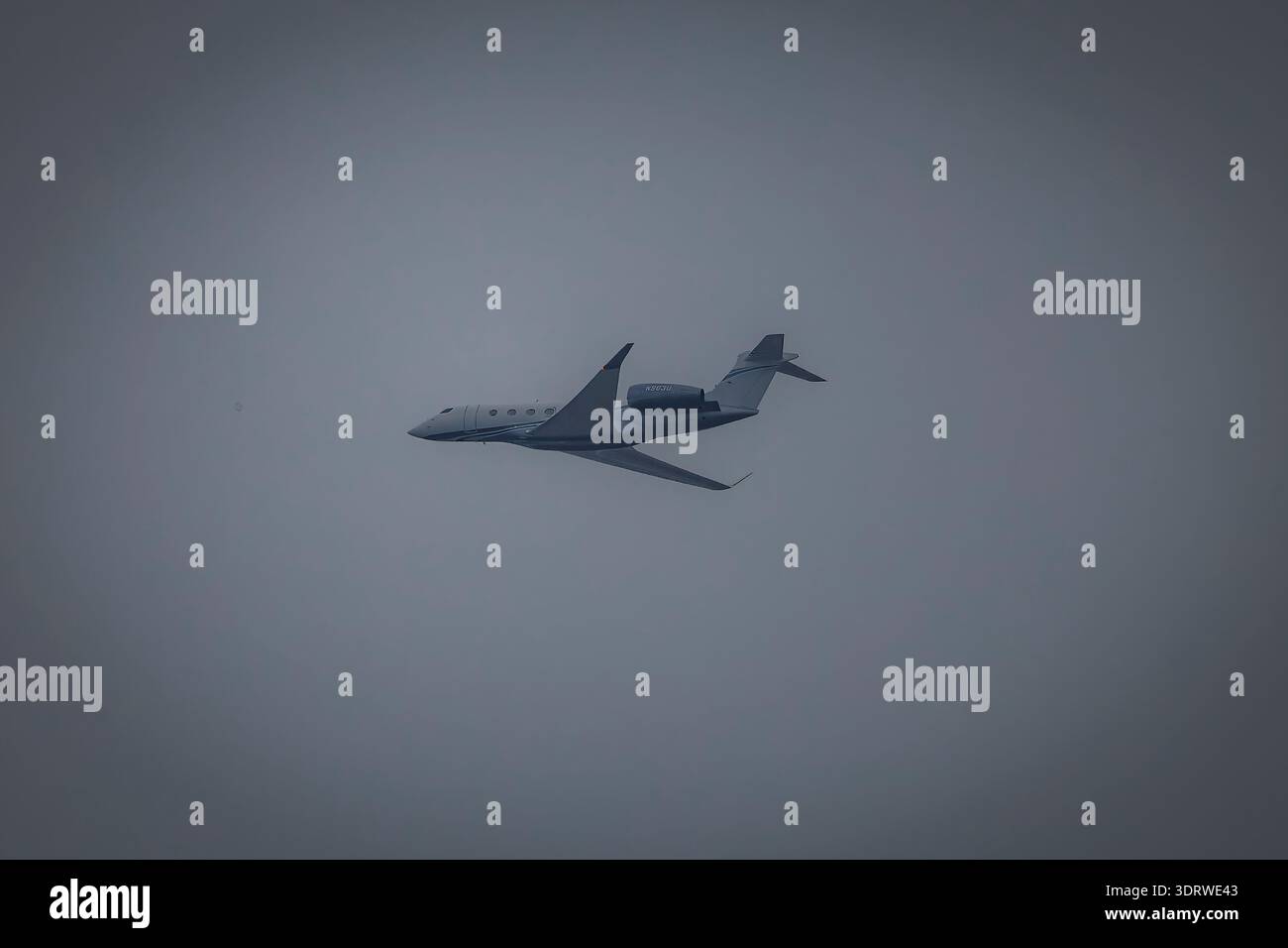 Jet privato che vola attraverso il cielo coperto, vista laterale degli aerei business durante il volo con il tempo nuvoloso Foto Stock