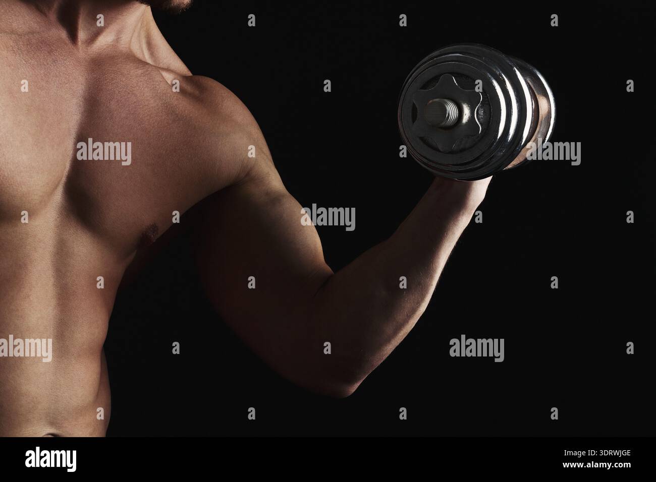 Allenamento muscolare in palestra durante le ore serali con pesi in mano Foto Stock