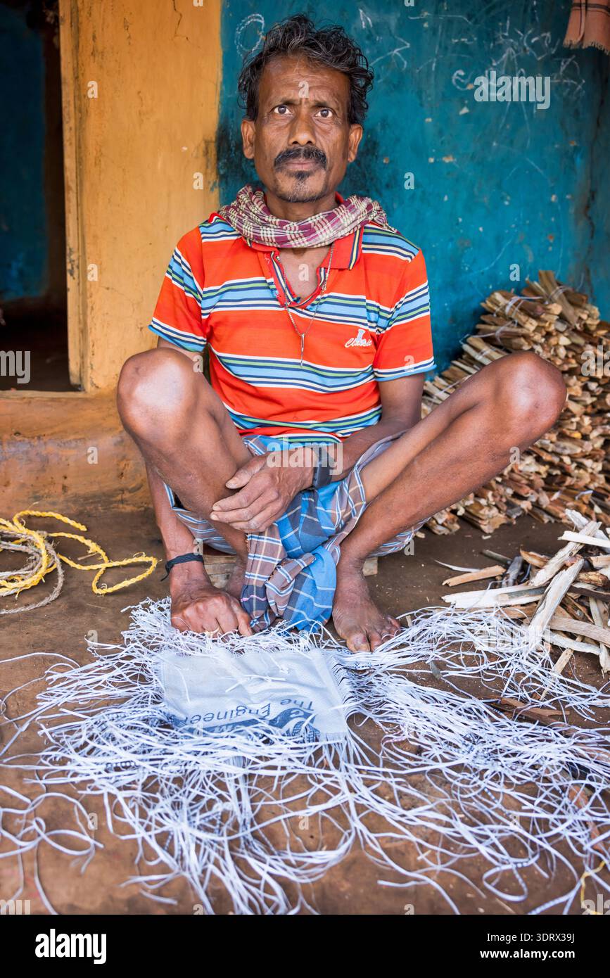 Uomo che fa pedine da vecchi sacchi di riso, Orissa, India Foto Stock