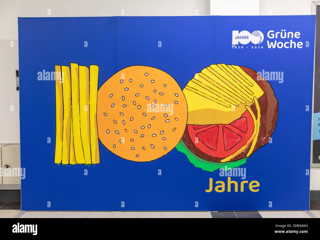 BERLINO, GERMANIA, 16 gennaio 2026: Foto di Cartoon illustrazione di un hamburger e patatine fritte su sfondo blu per il commercio internazionale Grüne Woche Foto Stock