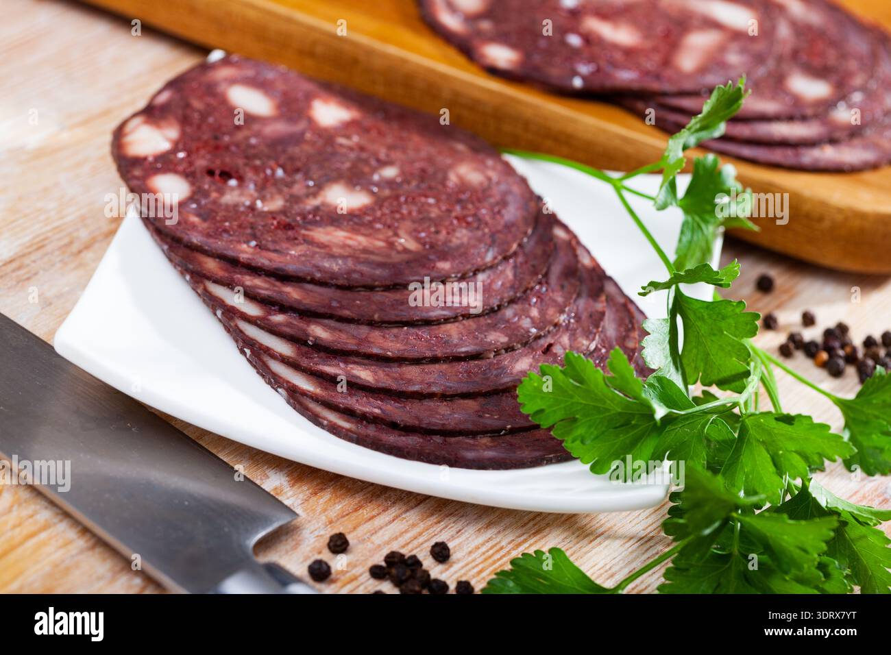 Budino di sangue della cucina europea servito con parley su piatto bianco su un tavolo di legno Foto Stock
