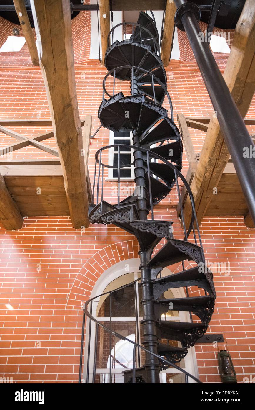 Alta scala a spirale nera (scala tortuosa) in un edificio di mattoni rossi, vista dal basso Foto Stock
