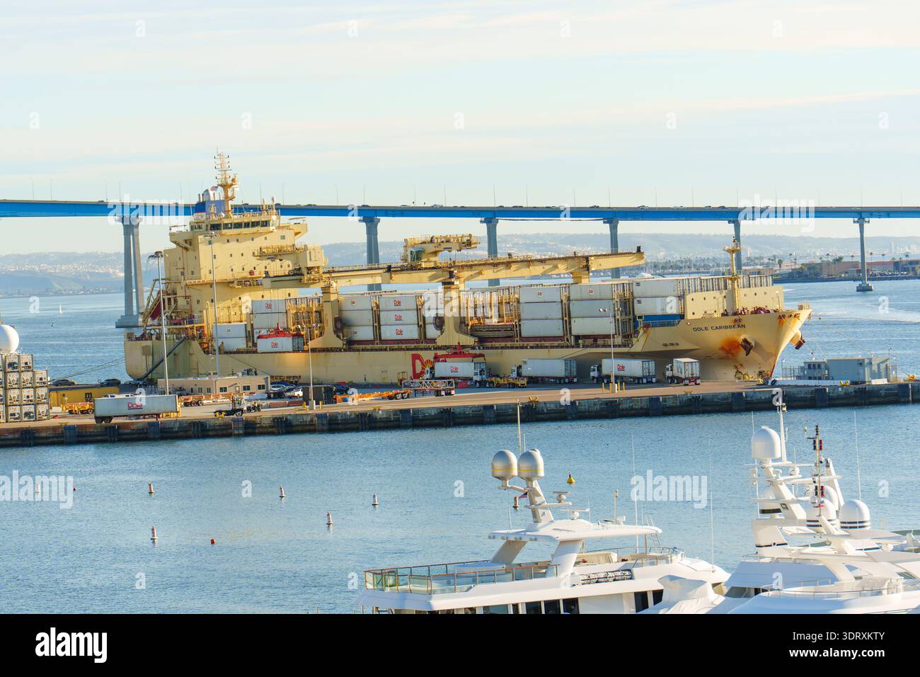 San Diego, California - 30 dicembre 2025: Grande nave portacontainer attraccata nel porto attivo di San Diego, con gru industriali, altre navi e l'ic Foto Stock