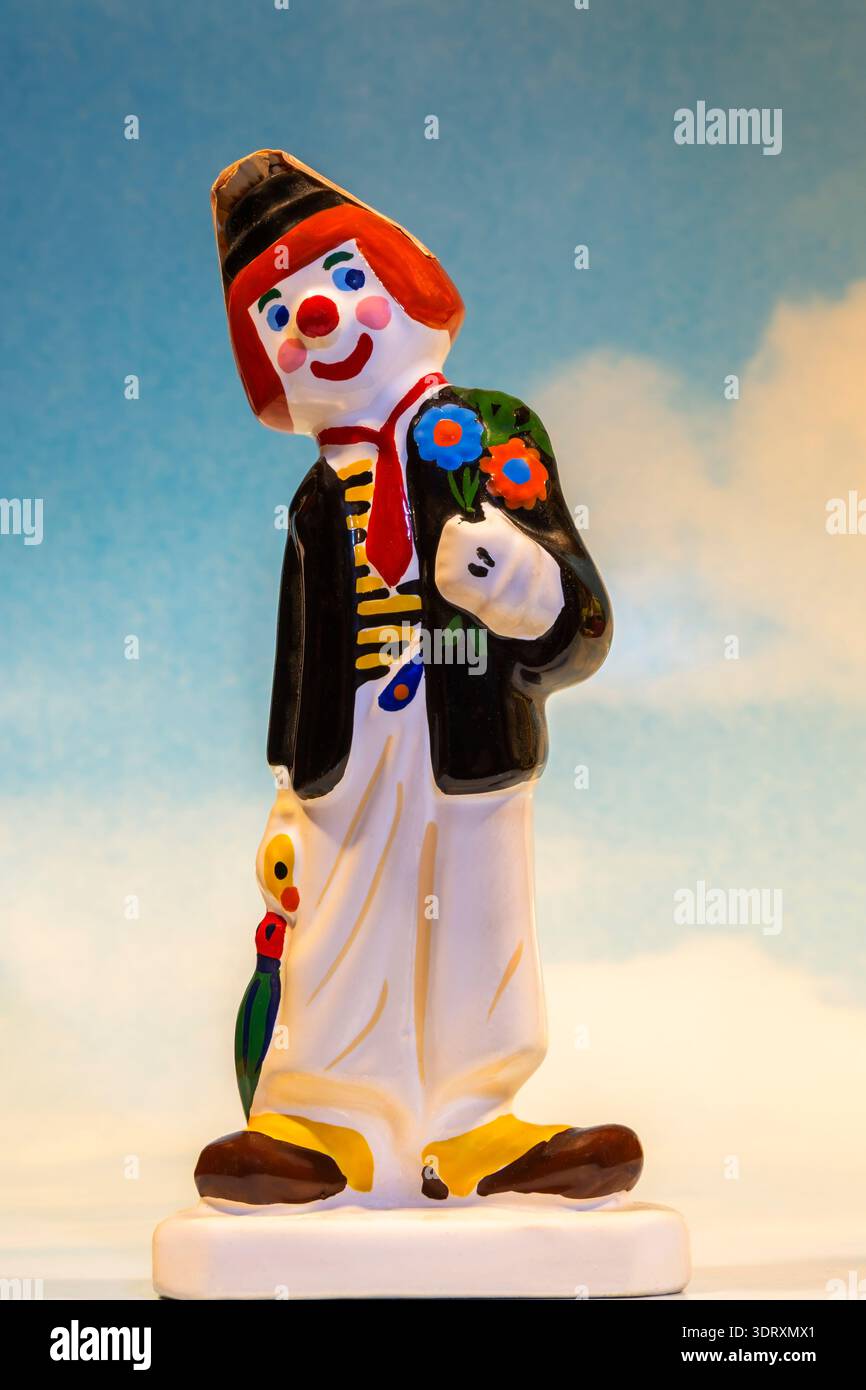 Primo piano della bottiglia di liquore in miniatura Forcoll a forma di un colorato clown circo sul cielo blu con sfondo nuvole bianche. Foto Stock