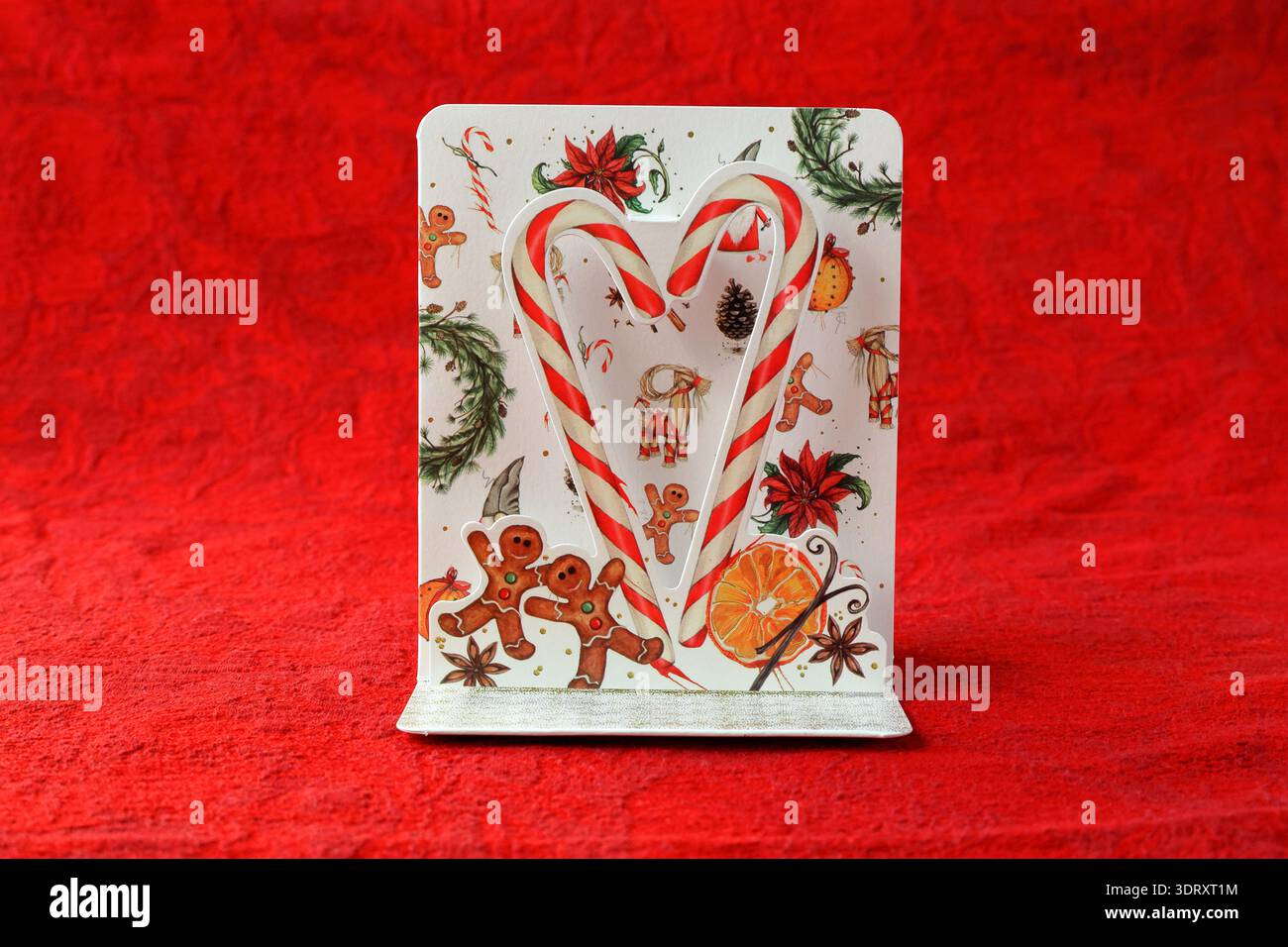 Biglietto di Natale con grande canna da zucchero. Omaggio o invito di benvenuto. Sfondo rosso. Foto Stock