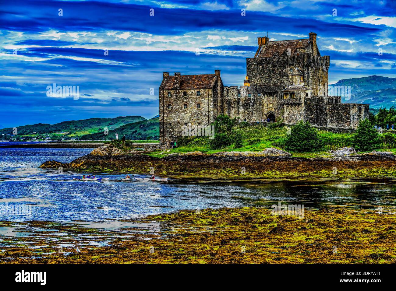 Il colorato castello di Eilean Donan kayak turisti Lochs Sea Lakes Highlands scozzesi Scozia. Castello costruito dal Clan Mackenzies nel 1200 Distrutto nel 1719 Foto Stock