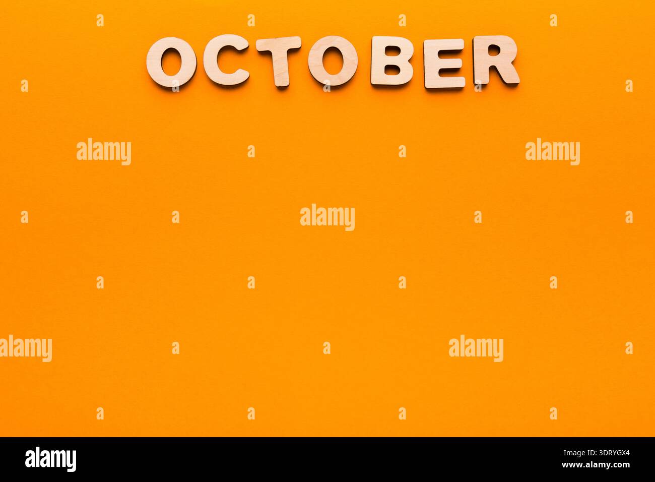 Mese di ottobre con lettere in legno su sfondo arancione brillante per il design stagionale Foto Stock