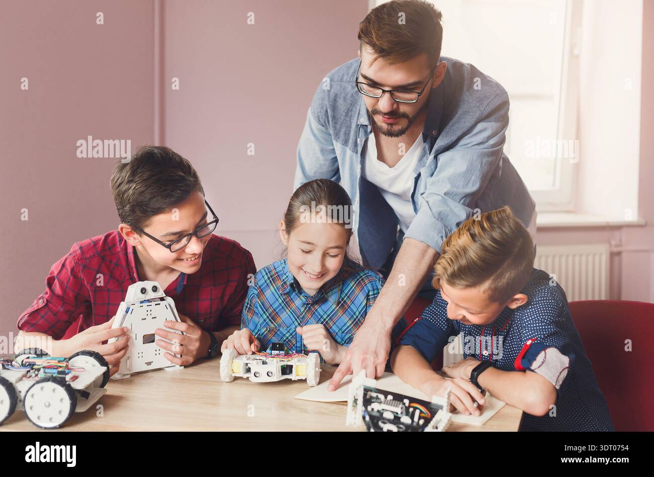 Gli studenti imparano a conoscere la robotica e la codifica in un'aula con un insegnante presente Foto Stock