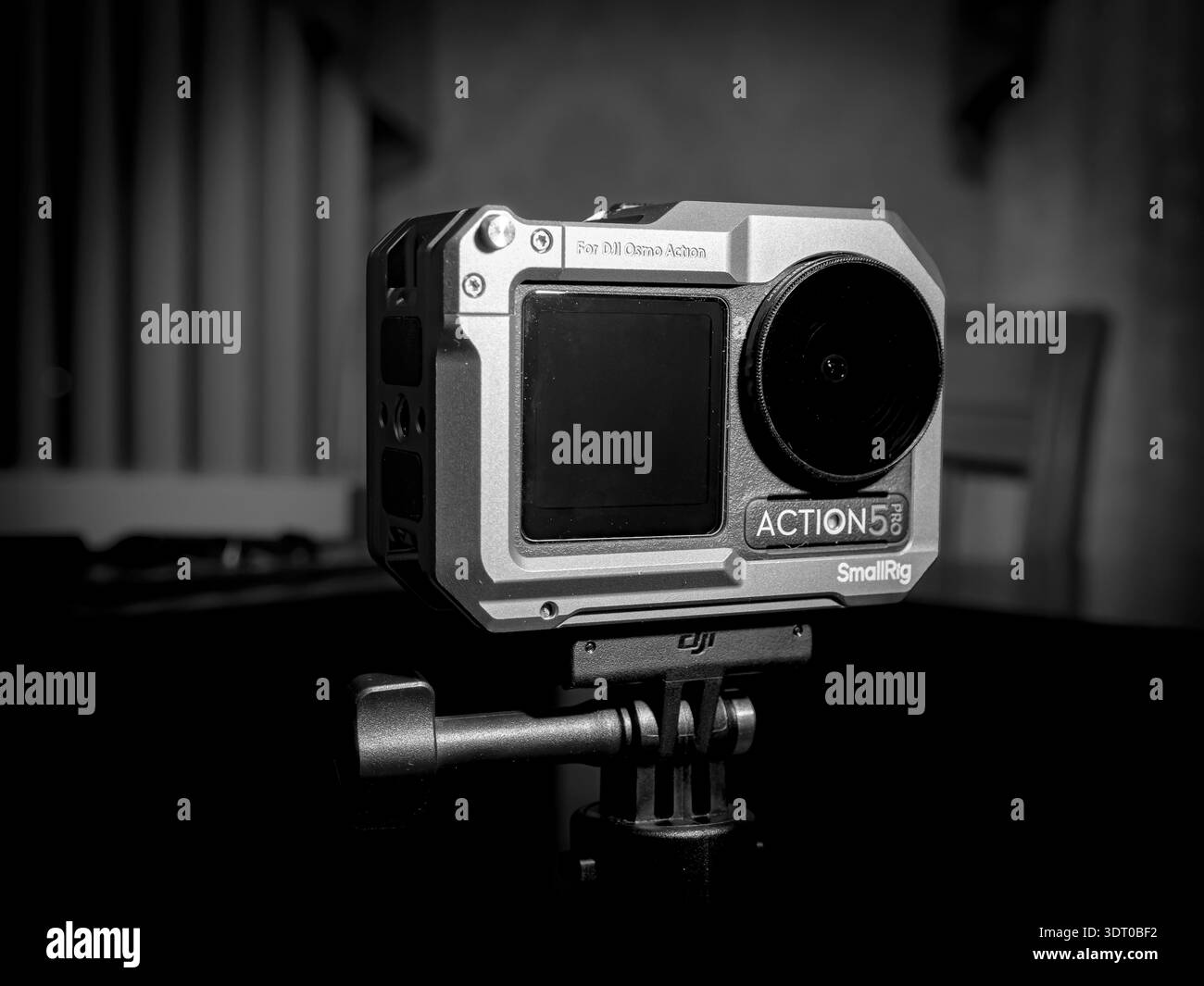 Primo piano della fotocamera DJI Osmo Action 5 Pro montata in una gabbia SmallRig su un treppiede, fotografata con illuminazione monocromatica Foto Stock