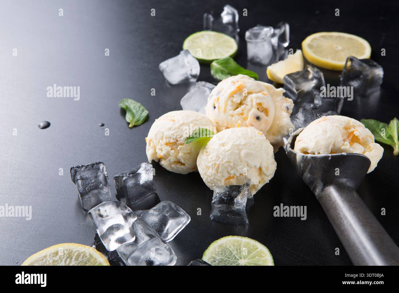 Gelato al limone su una superficie scura con zecca e cubetti di ghiaccio sullo sfondo Foto Stock