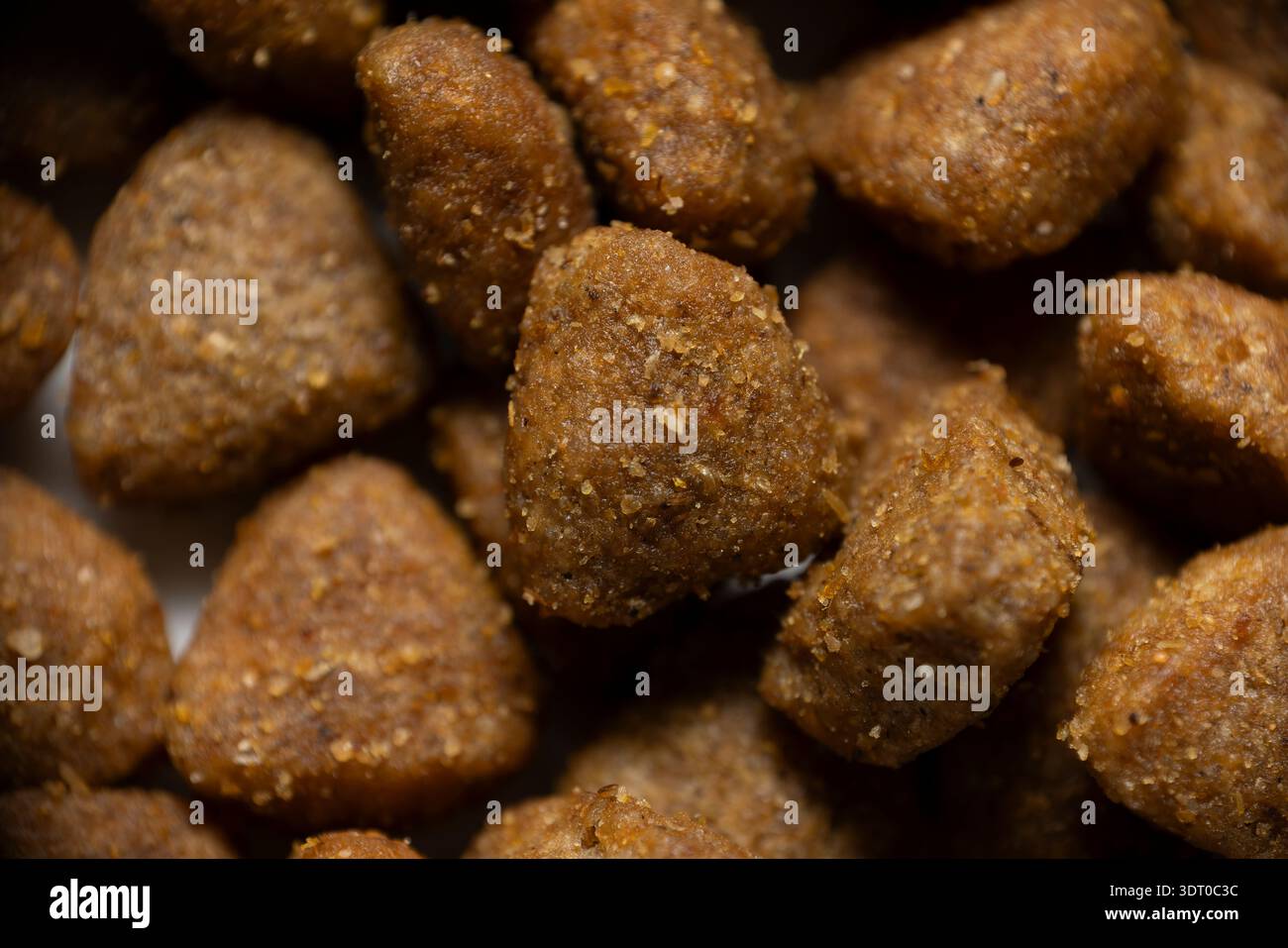 Primo piano di pellet di alimenti secchi marroni per animali domestici che mostrano texture e forme dettagliate, che rappresentano l'alimentazione animale e la cura degli animali Foto Stock