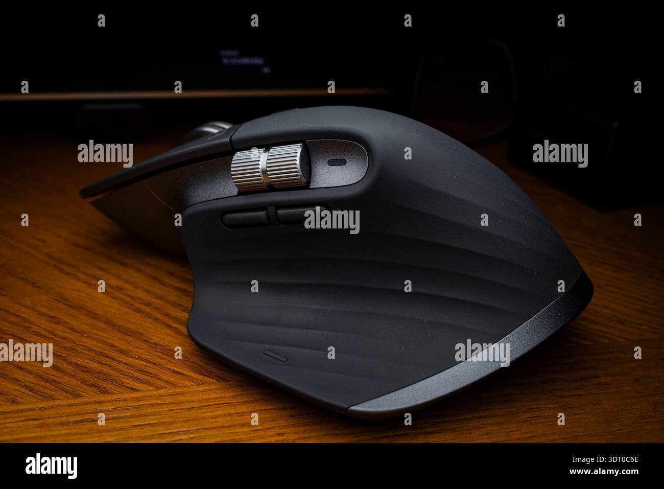 Primo piano di un mouse per computer wireless Logitech MX Master su una scrivania in legno, con design ergonomico e rotelle di precisione Foto Stock