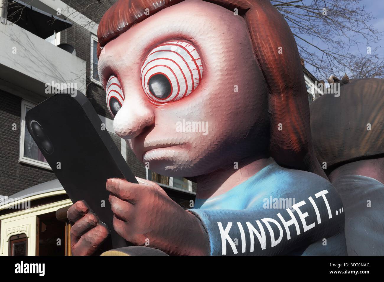 Ragazza che fissa il telefono cellulare, auto motrice per la dipendenza giovanile dai social media, divieto dei social media, auto motrice del costruttore di carri Jacques Tilly, Duesseldorf Ros Foto Stock