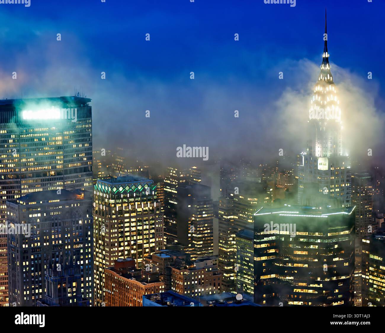 La vista di Manhattan al tramonto mostra edifici illuminati e nebbia che ricoprono alcune strutture. Lo skyline della città è visibile con luci scintillanti. Foto Stock