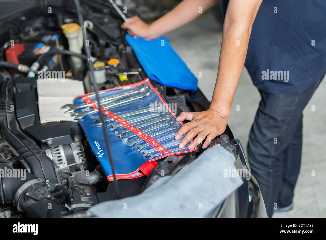 Riparazione meccanica dell'auto a casa. Meccanico, tecnico con kit attrezzi per la riparazione di auto per controllare il motore di un'auto. Assistenza auto, riparazione, riparazione, manutenzione Foto Stock