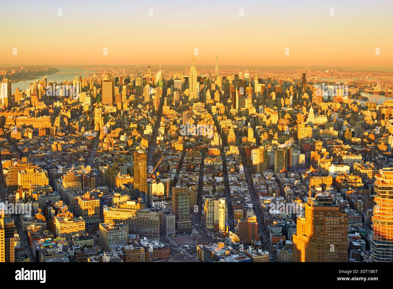 Vista di Manhattan a New York con edifici e strade alti. La scena cattura la città durante il tramonto con un bagliore arancione. Foto Stock