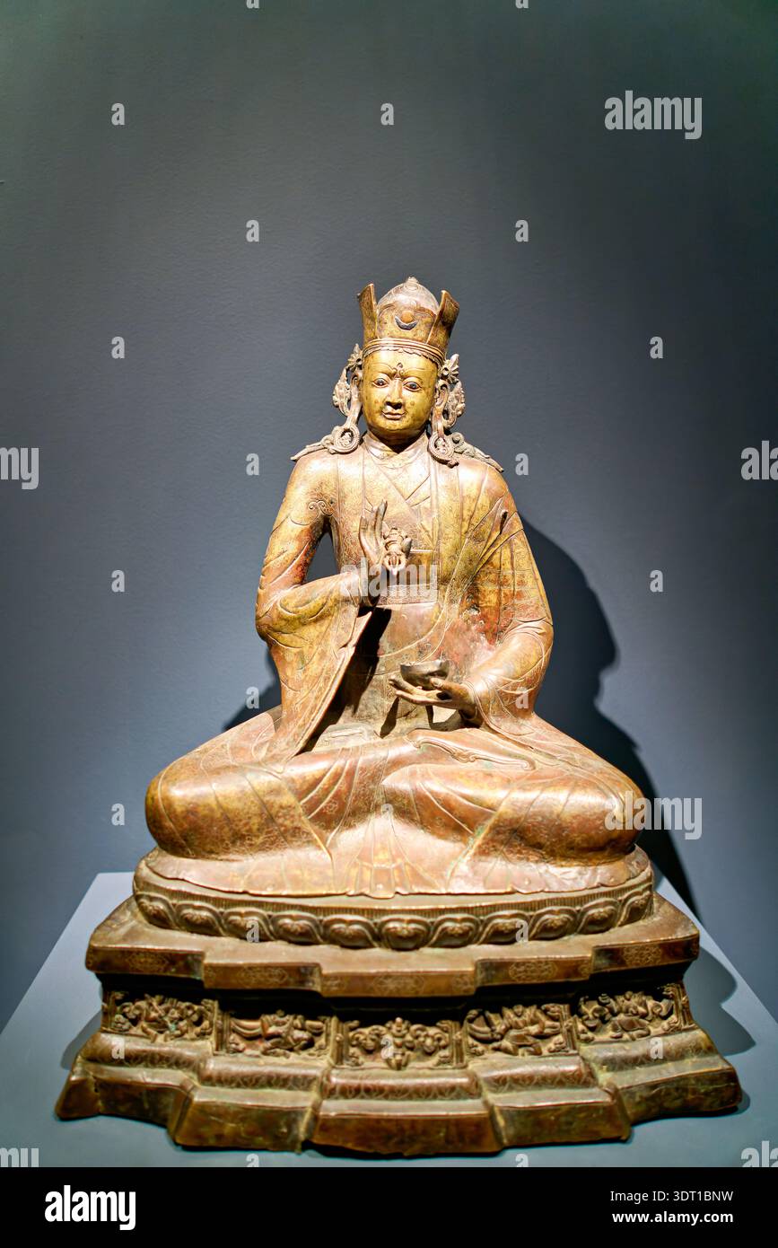Una figura seduta indossa una corona e regge un oggetto mentre è seduta a gambe incrociate nella Asian Art Gallery di Manhattan, New York. Foto Stock