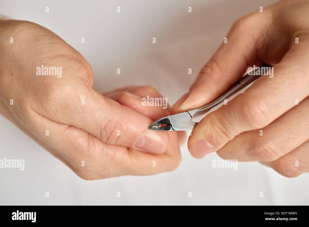 Persona che rimuove la pelle in eccesso dalle punte delle dita per unghie pulite e sane Foto Stock