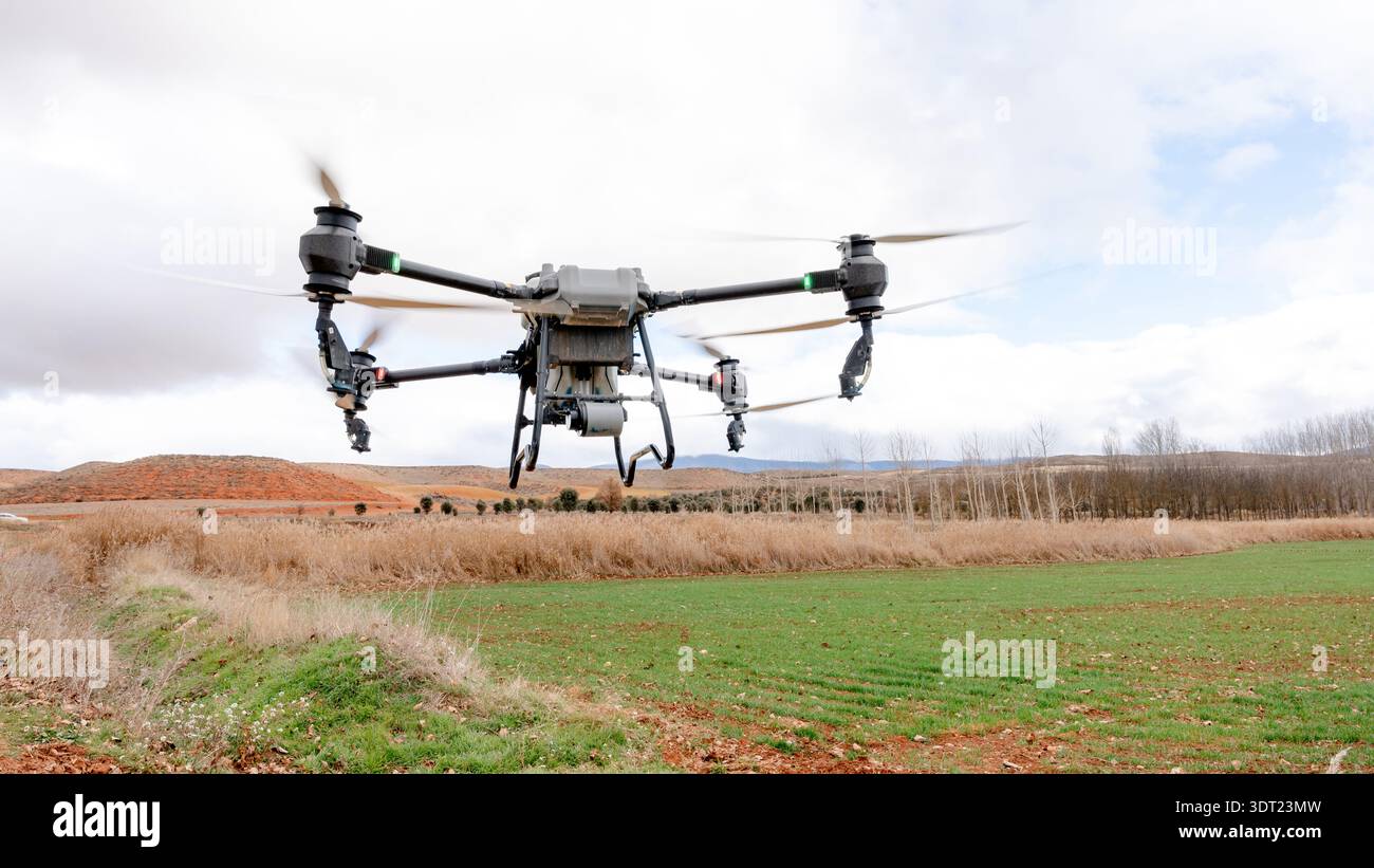 Un drone agricolo che sorvola il campo di grano irrigato ad Alfambra, Teruel, Spagna. Sistema di irrorazione fertilizzante liquido visibile durante il sistema Precision Farming Foto Stock