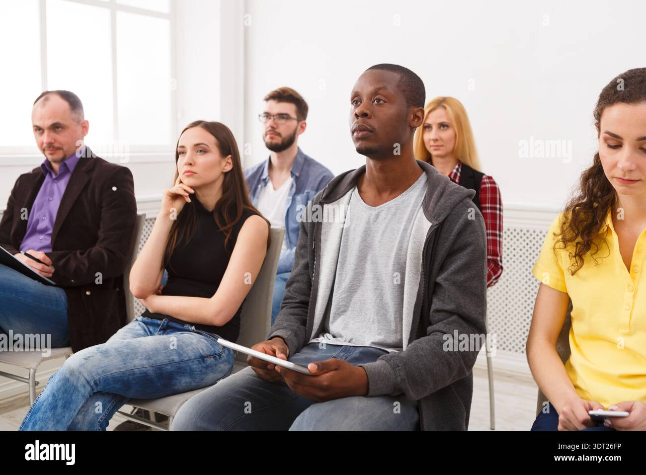 Le persone partecipano a una sessione in una Bright Room con sedie e finestre nel pomeriggio Foto Stock
