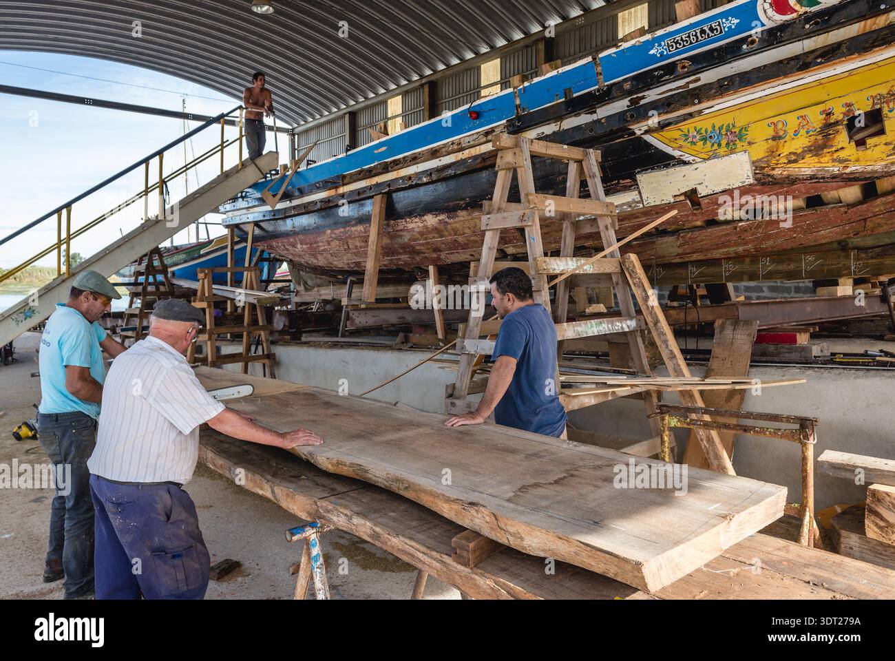 I lavoratori del cantiere navale in cui i tradizionali fiume Tago barche sono costruiti e riparati in Sarilhos Pequenos village a Moita comune, Portogallo Foto Stock