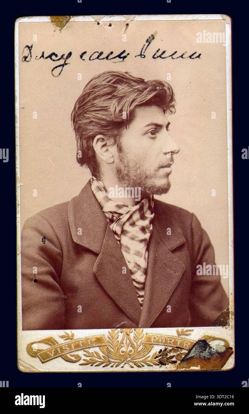 Questa antica fotografia color seppia del 1902 cattura un giovane Joseph Stalin, allora conosciuto come Iosif Vissarionovich Dzhugashvili. Il futuro leader sovietico è raffigurato con una testa piena di capelli ondulati, una barba e un cravat a quadri, suggerendo un periodo prima della sua ascesa alla ribalta politica. Il testo scritto a mano in russo adorna la parte superiore dell'immagine. Foto Stock