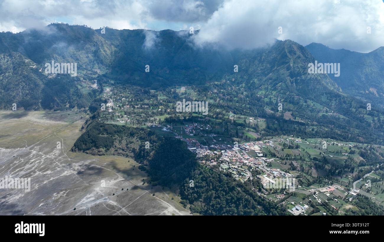 Cemoro Lawang si arrocca sul bordo della caldera, sui campi di patchwork e sui villaggi incorniciati da torreggianti pareti vulcaniche e nuvole ondulate. Foto Stock