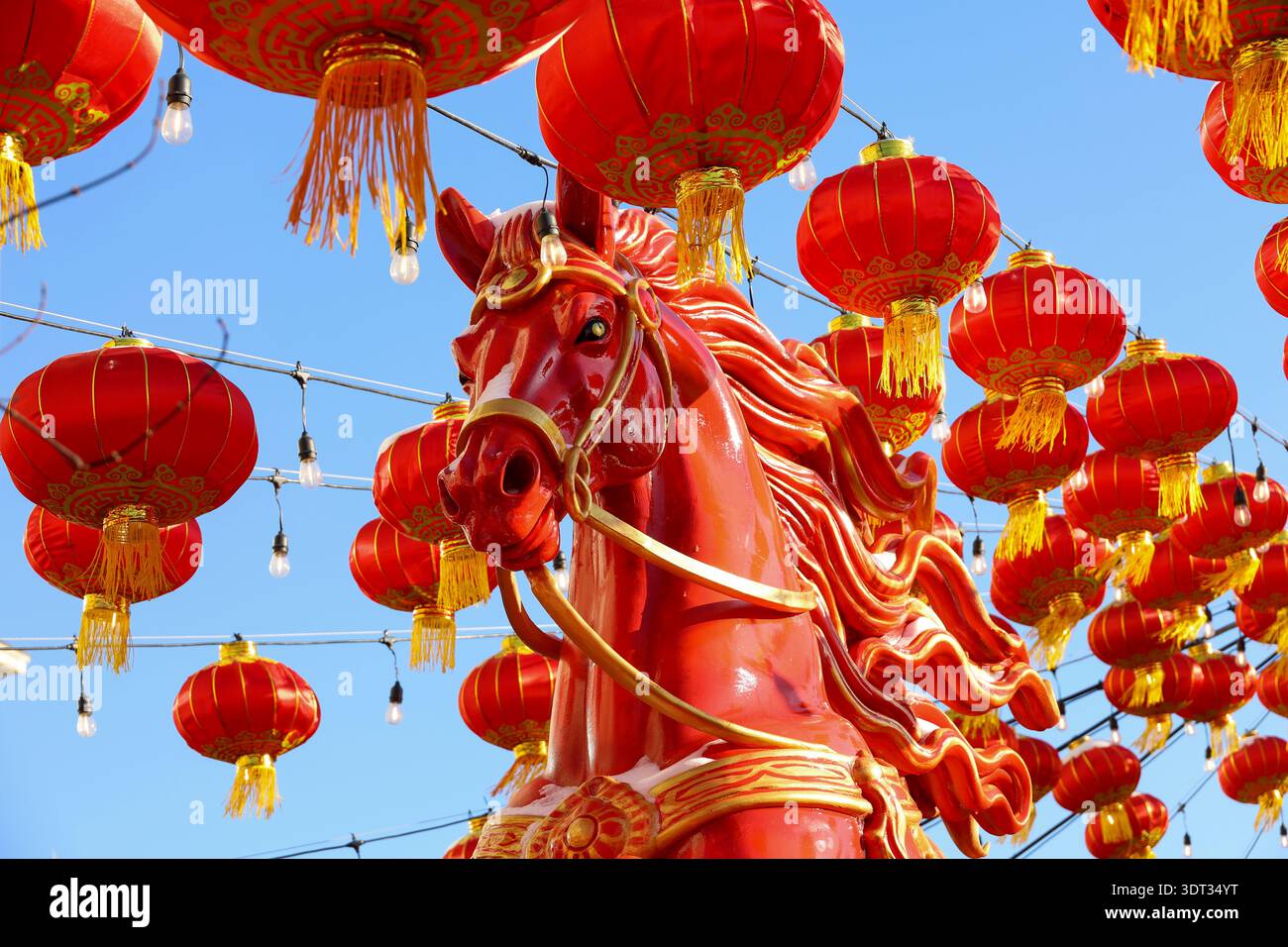 Cavallo rosso e lanterne rosse sullo sfondo blu del cielo. Decorazioni cinesi festive, festa del nuovo anno lunare in Asia Foto Stock