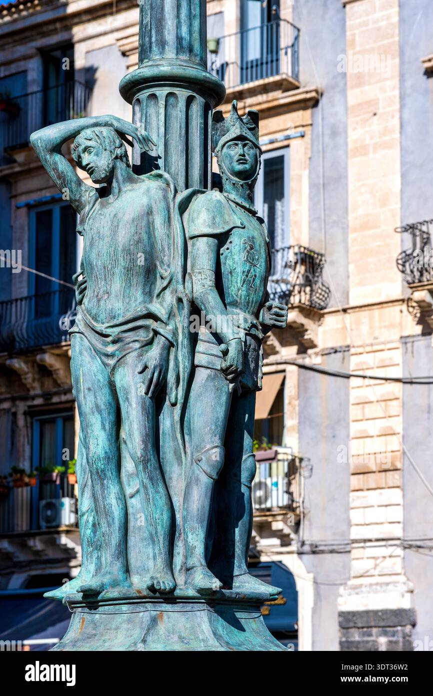 Dettaglio di una base scultorea in bronzo a candelabro raffigurante un cavaliere in armatura e una figura drappeggiata in Piazza Università, Catania, Sicilia, Italia. Foto Stock
