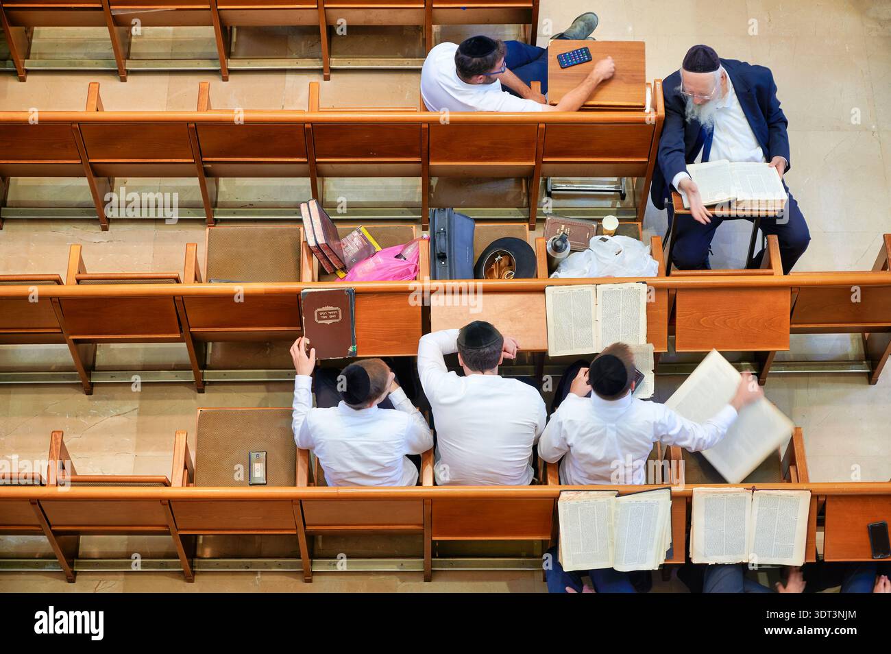 Le persone sono impegnate nella preghiera e nello studio all'interno della sinagoga Hurva a Gerusalemme. Libri e oggetti personali sono visibili tra le panchine. Foto Stock