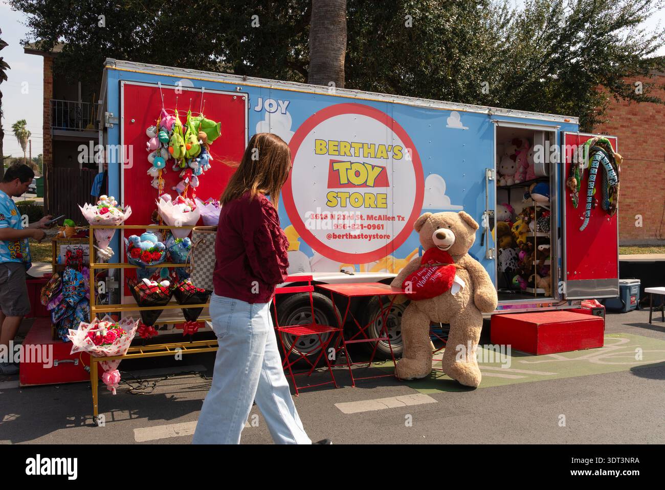 Young Woman passeggia presso il Bertha's Toy Store al Main Street Market, un mercato all'aperto nel centro di McAllen, Texas, Stati Uniti. SOLO PER USO EDITORIALE. Foto Stock