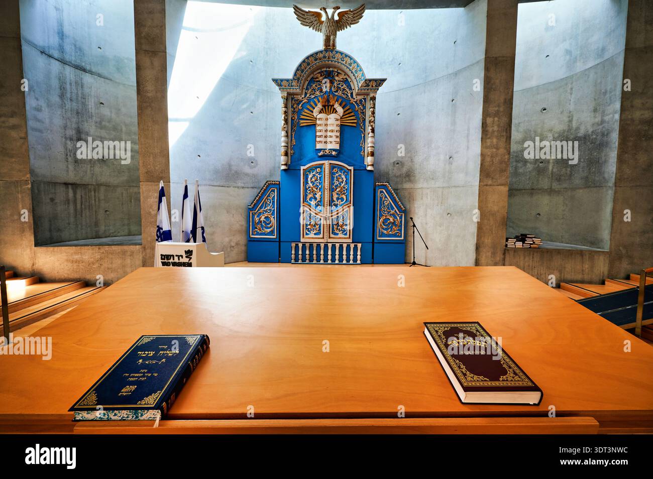 La sinagoga di Yad Vashem mostra i rotoli della Torah e un'arca blu ornata. Vengono visualizzati dei flag. Questo spazio onora le vittime dell'Olocausto. Foto Stock