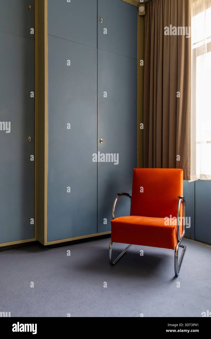 Camera da letto blu con sedia arancione luminosa presso Sonneveld House, Rotterdam, costruita all'inizio degli anni '1930 in stile funzionale da Brinkman en Van der Vlugt. Foto Stock