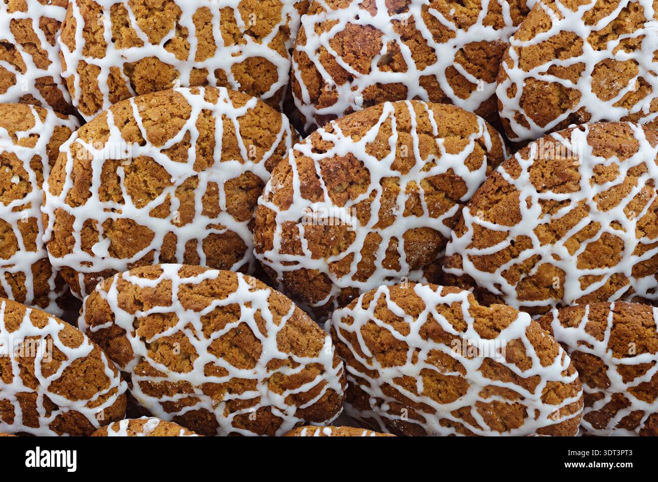 Classici biscotti fatti in casa con farinata d'avena decorati con glassa di zucchero bianco liscio, che mostrano la loro consistenza rustica e l'aspetto caldo e cotto. Vista ravvicinata, a. Foto Stock