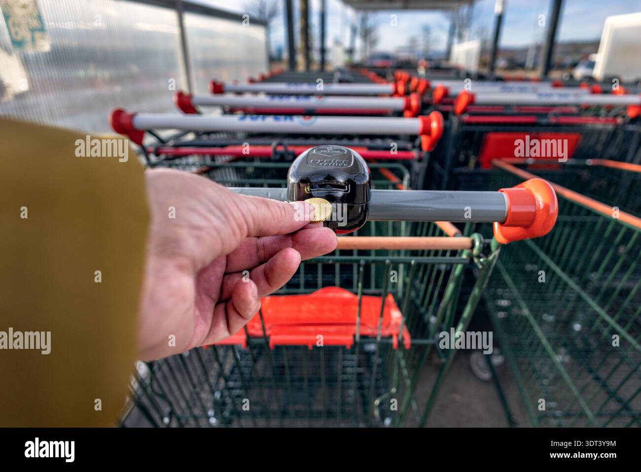 Digione, Francia - 2 febbraio 2026: Inserimento manuale di una moneta o di un gettone in un carrello per supermercati Super U. Questa routine quotidiana di shopping e shopping mostra una persona a noi Foto Stock