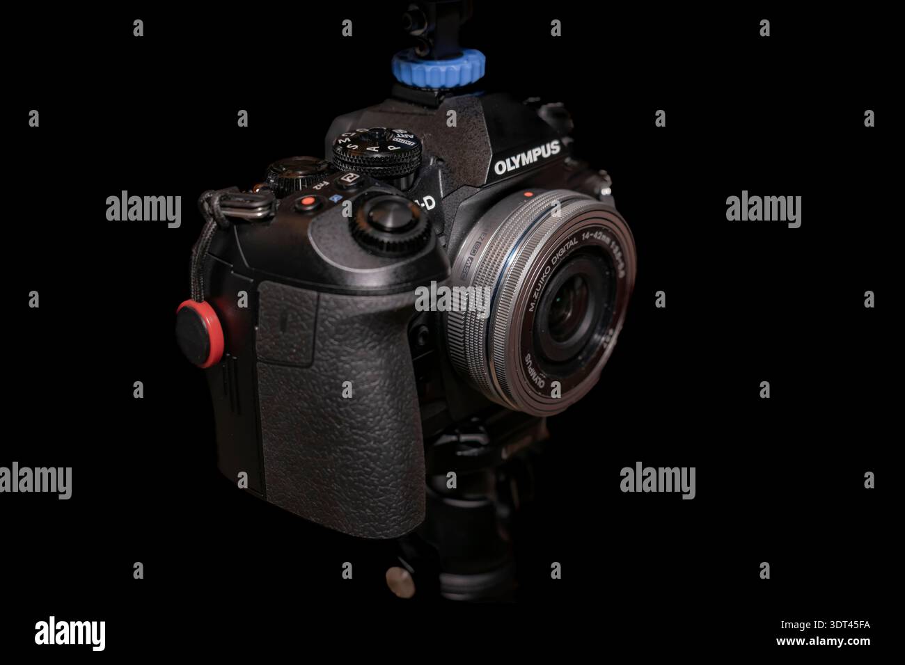 Primo piano della fotocamera digitale Olympus con obiettivo M.Zuiko da 14–42 mm montato su treppiede su sfondo nero Foto Stock