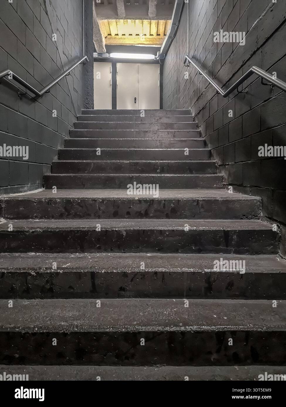 Moderna rampa di scale con gradini di cemento che portano in alto, verticale. Uscita di emergenza all'interno della stazione della metropolitana zona Universitaria di Barcellona, Spagna Foto Stock