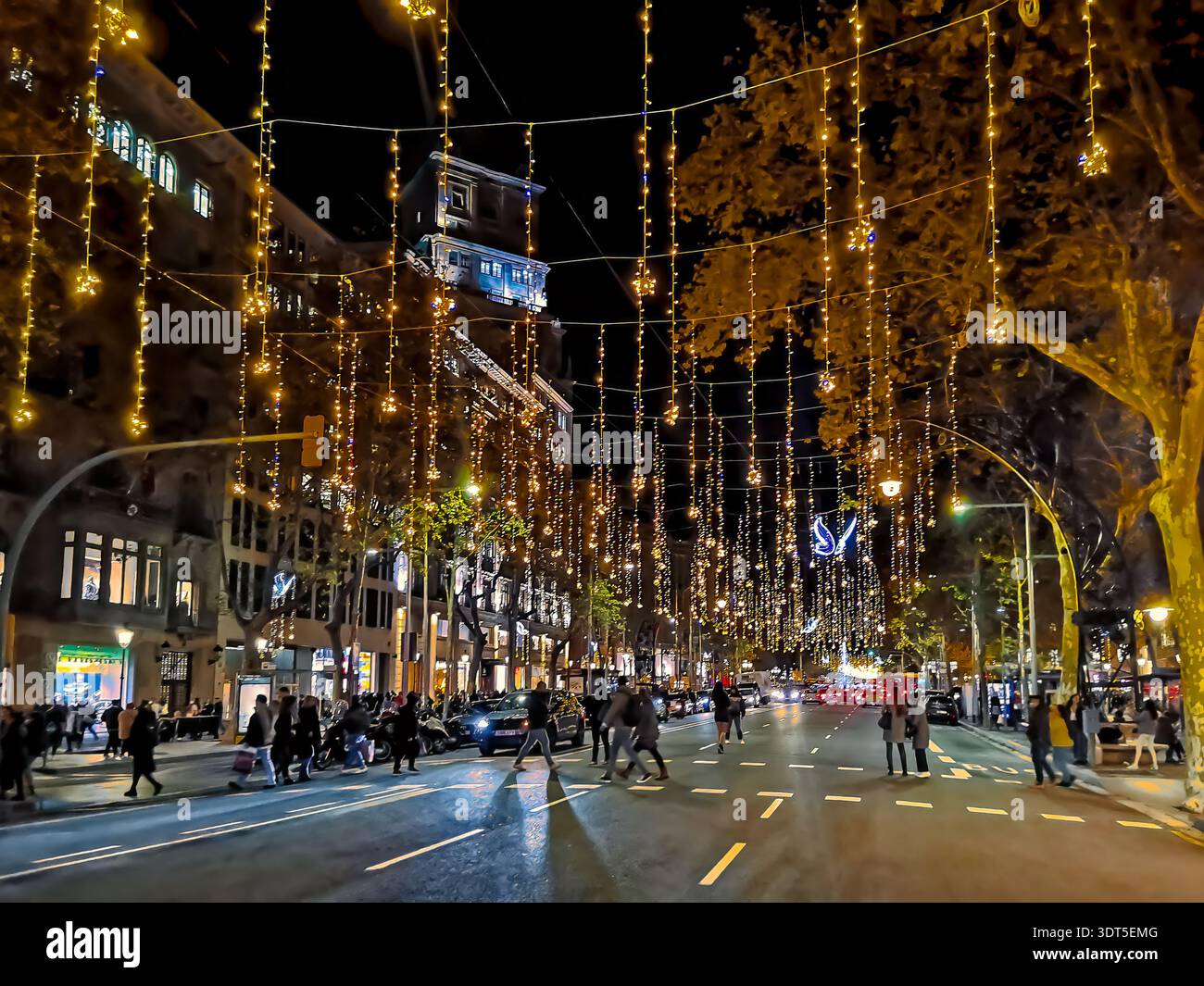 Ghirlande sospese in oro natalizio con farfalle blu sulla strada con auto sul Passeig de Gracia a Barcellona, Spagna. Illuminazione stradale festiva - Immagine stock catturata con smartphone