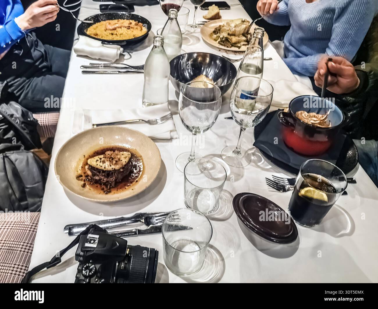 Autentica scena di vita reale di amici che condividono un pasto mediterraneo in un ristorante. Vista dall'alto di un tavolo festivo con paella e vino. Saragozza, Spagna - Immagine stock catturata con smartphone