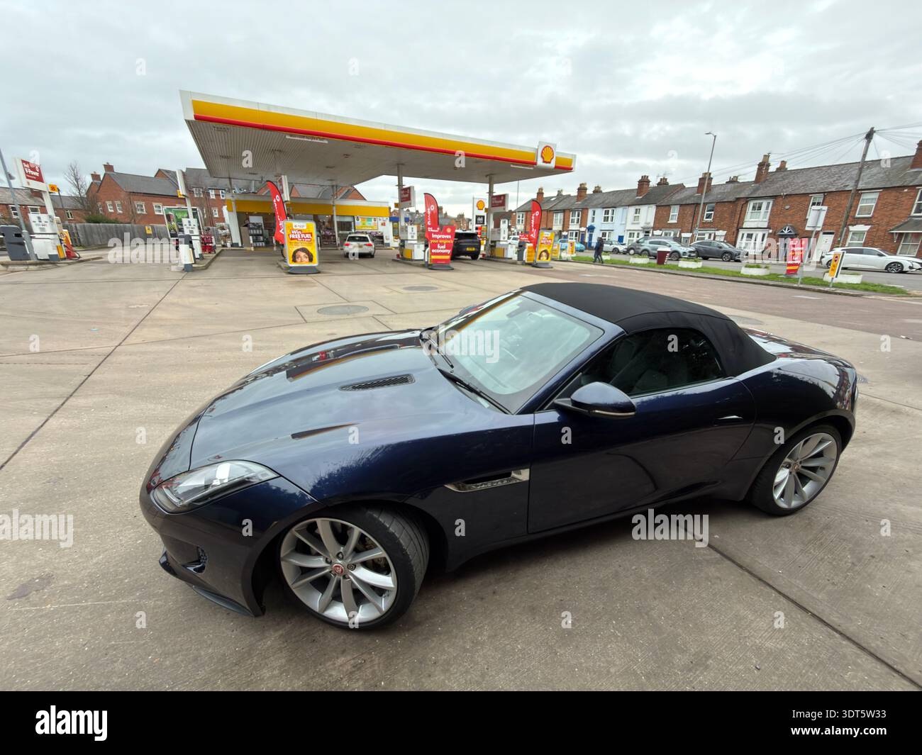 Jaguar F-Type convertibile blu scuro parcheggiata presso un piazzale Shell a Stratford-upon-Avon, Warwickshire, Inghilterra, Regno Unito. Foto Stock