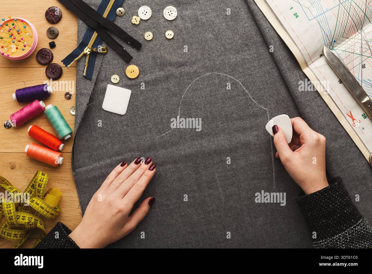 Lavorare sul tessuto con gli strumenti in un'impostazione di cucitura creare un progetto per un articolo di abbigliamento Foto Stock