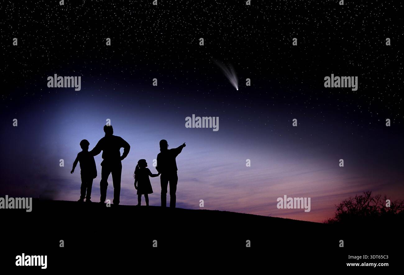 La famiglia sta insieme su una collina che guarda su una cometa luminosa nel cielo notturno. Le stelle brillano sullo sfondo mentre si godono la vista con una somma chiara Foto Stock