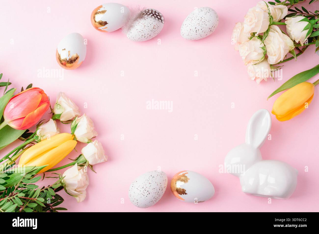 Sfondo pasquale con uova decorate, coniglietto in ceramica e fiori primaverili disposti intorno al centro vuoto su sfondo rosa pastello. Vista dall'alto, disposizione piatta, copia Foto Stock