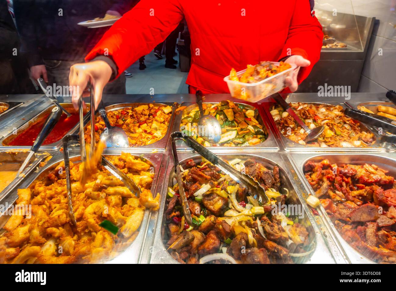 Una persona che si occupa di mangiare in un buffet cinese self-service in un ristorante di Londra, Regno Unito Foto Stock