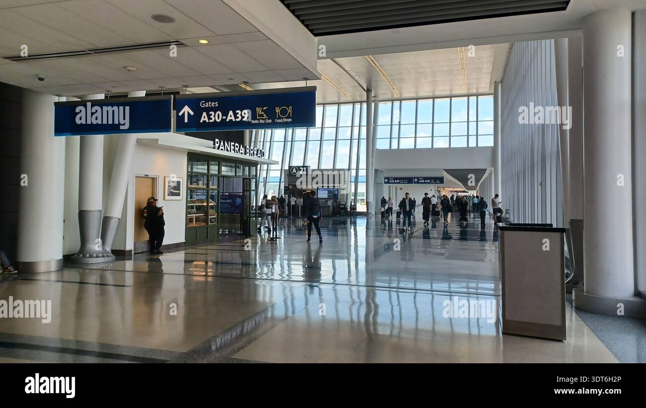 Charlotte, North Carolina, USA - 9 giugno 2025: Le persone attraversano un moderno terminal aeroportuale; trasmette l'atmosfera di viaggio e transito. Foto Stock