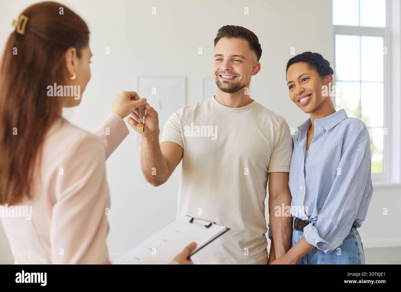 Agente immobiliare che dà le chiavi da un nuovo appartamento a una coppia felice, i clienti acquistano o affittano una proprietà Foto Stock