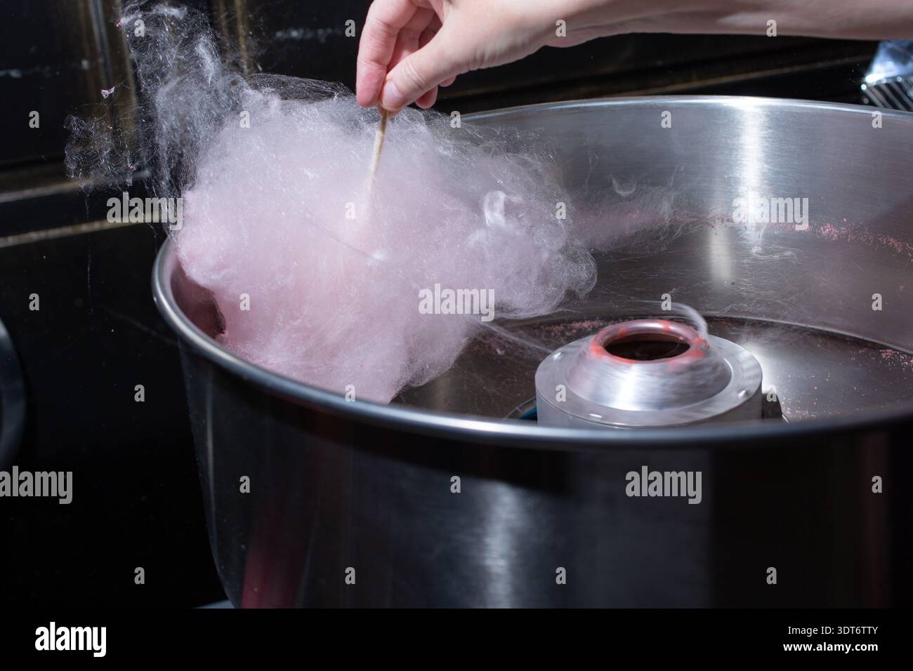Una vista di una caramella di cotone filata a mano all'interno di una macchina per la produzione di caramelle di cotone. Foto Stock
